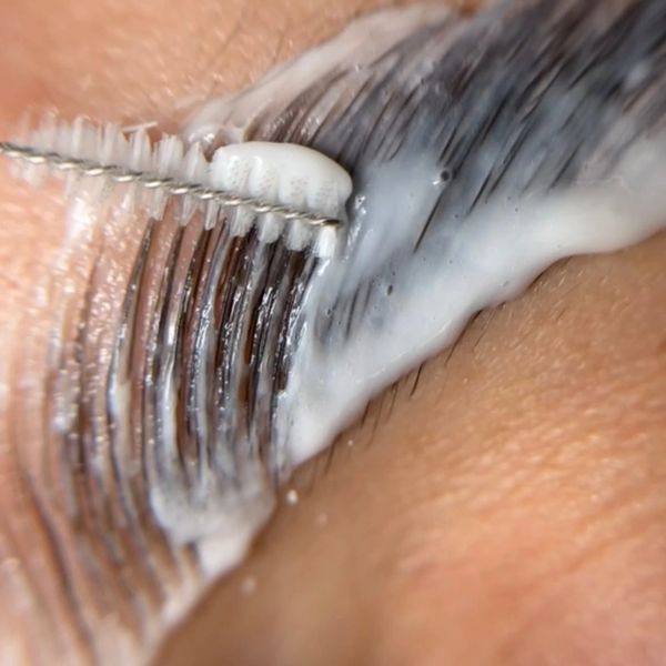Close-up of a beauty brush applying cream to eyelashes.