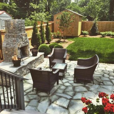 Cozy backyard patio with stone fireplace and wicker furniture.