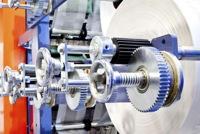 Close-up of metallic gears and rollers in industrial machinery.