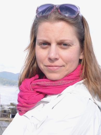 Woman wearing pink scarf and sunglasses on her head, outdoors near water.