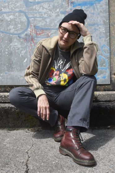 Person sitting on the ground wearing a beanie, glasses, and brown boots.