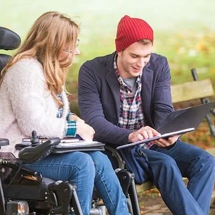 A disability support worker assisting a lady in a wheelchair.