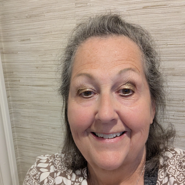 Smiling woman with gray hair and patterned shirt.
