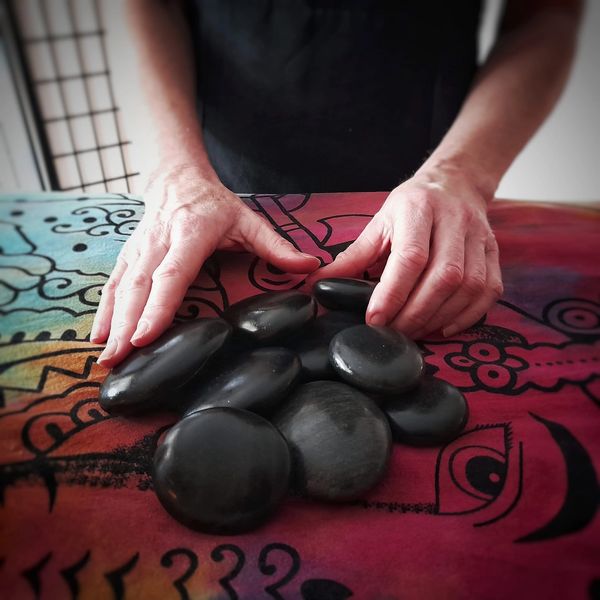 Hot stones shown sitting on top of massage bed ideal for a relaxing massage on a cold day
