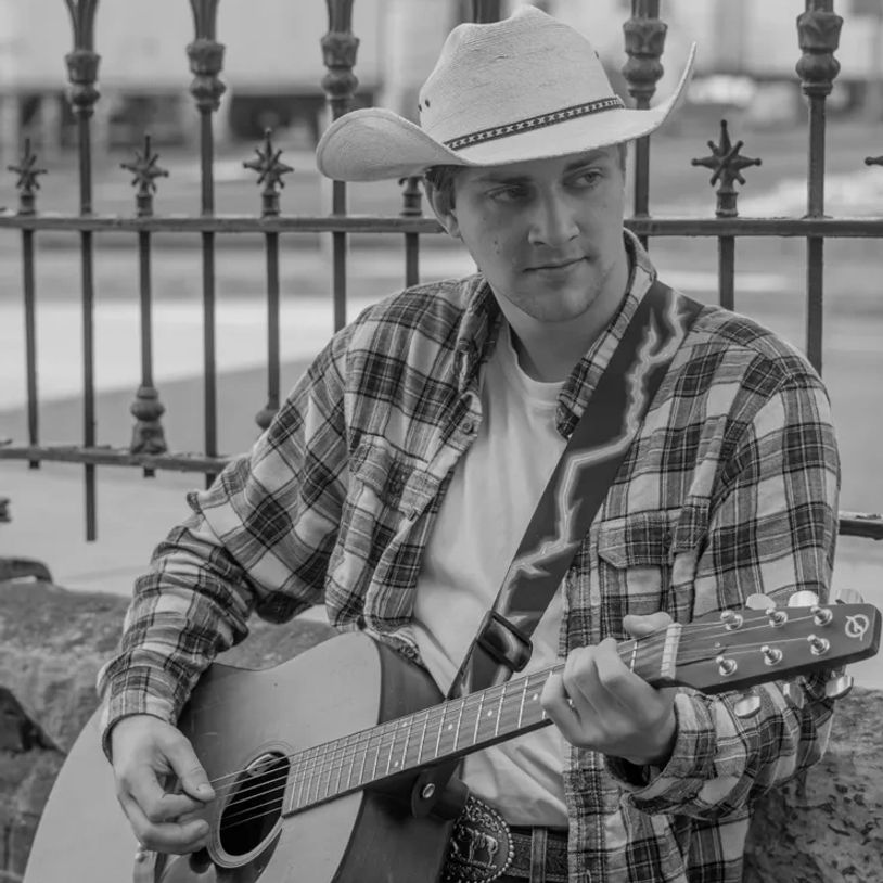 Man in a cowboy hat playing acoustic guitar.