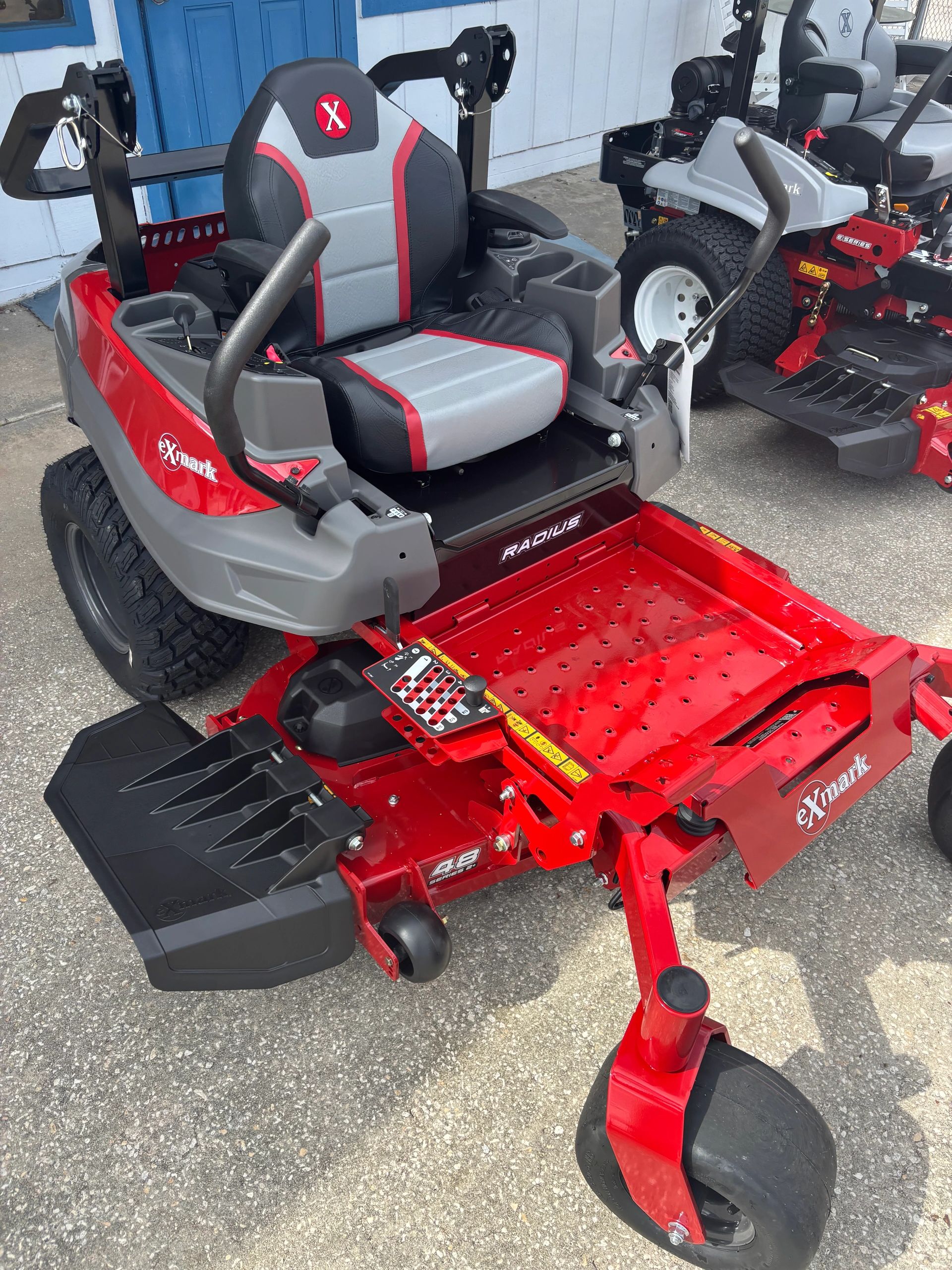 Red and gray Exmark Radius zero-turn lawn mower with padded seat and control levers.