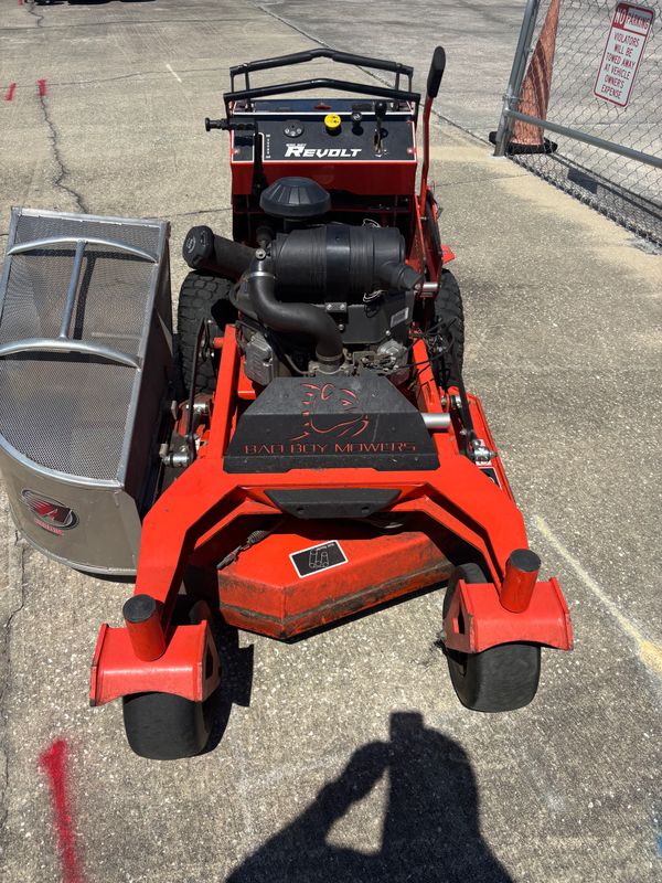 A red Bad Boy Mowers lawn mower with a ReVolt engine on concrete pavement.