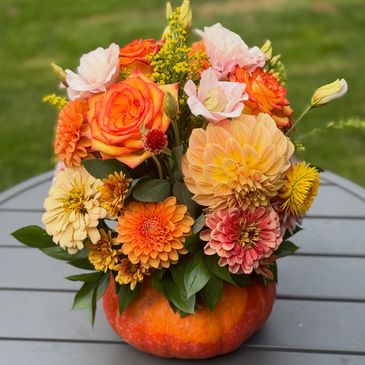 Colorful autumn flowers in a pumpkin vase.