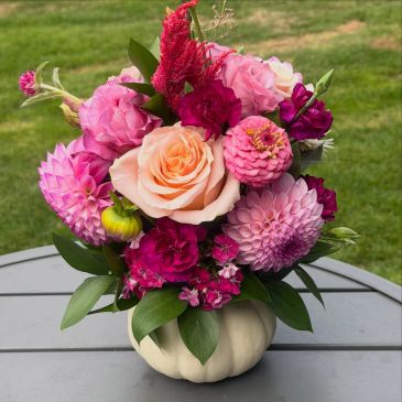 Colorful flower arrangement in a white pumpkin vase.