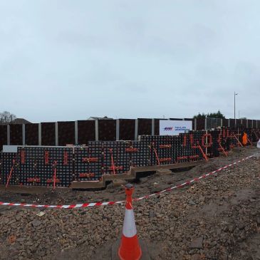 Construction site with reinforced concrete wall sections and safety cones.