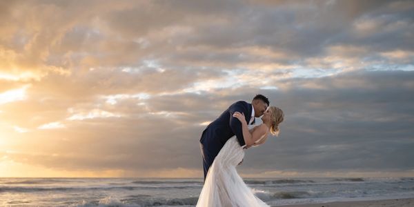 Couple kissing on the beach at sunset.