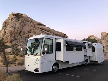 White RV parked near rocky terrain during dusk.