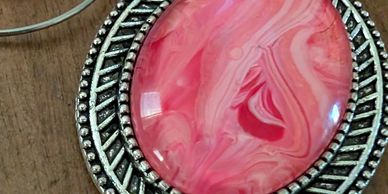 Pink marbled stone jewelry with silver accents on a wooden surface.