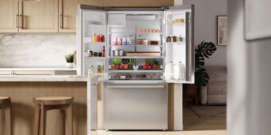 Modern kitchen with an open stainless steel refrigerator full of groceries.