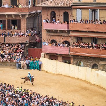 A jockey on a horse races in a crowded arena during a traditional event.