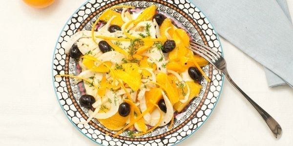 Fresh citrus and olive salad with fennel on a decorative plate.