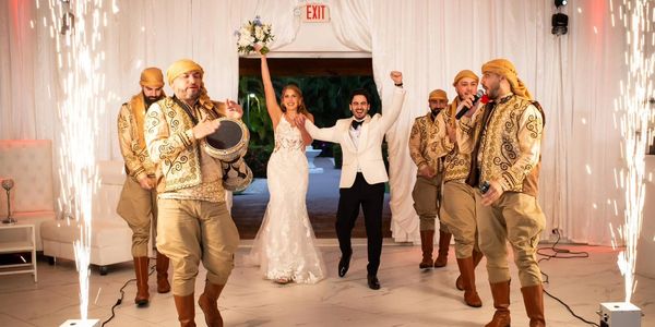 Newlyweds celebrating with traditional music and fireworks indoors.
