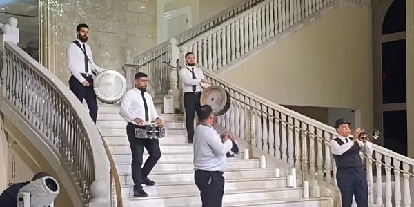 Musicians performing on a grand staircase with traditional drums and trumpet.