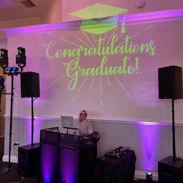 DJ setup at a graduation party with congratulatory message projected.