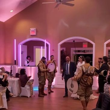 Traditional musicians perform at a wedding reception with bride and groom dancing.