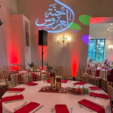 Elegant banquet hall with red lighting and Arabic calligraphy projection.