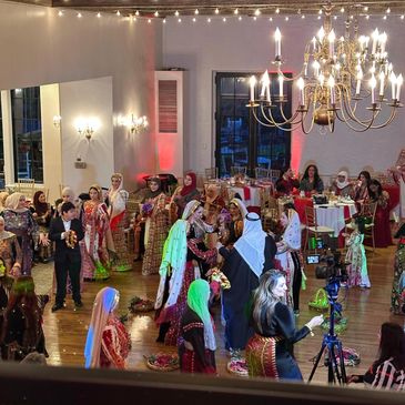 A vibrant cultural celebration with traditional attire and dancing indoors.