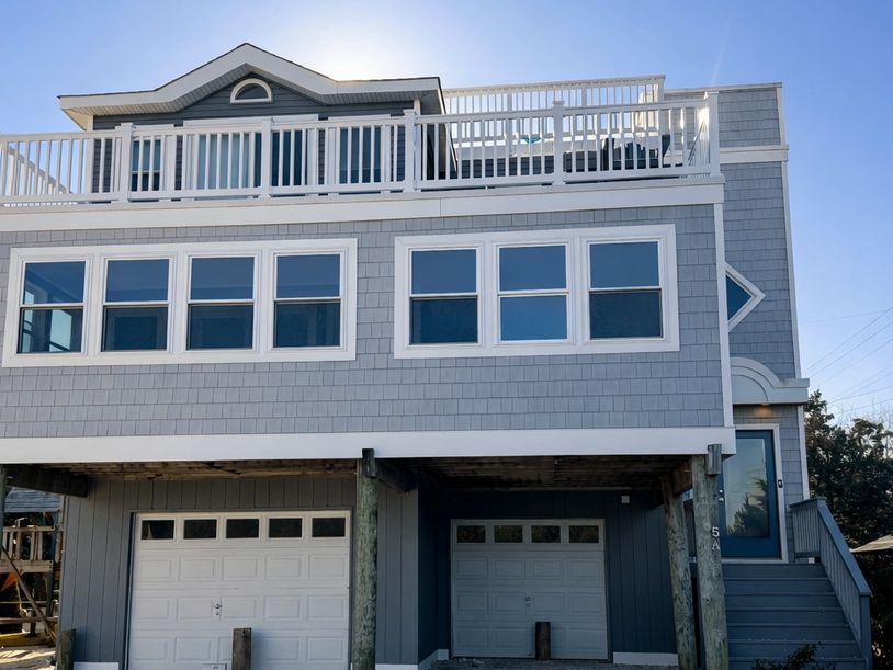 Modern gray house with two garages and rooftop deck.