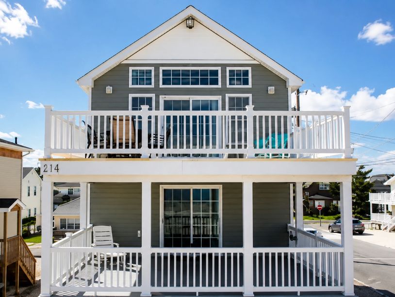 Two-story gray house with white railings and balconies.