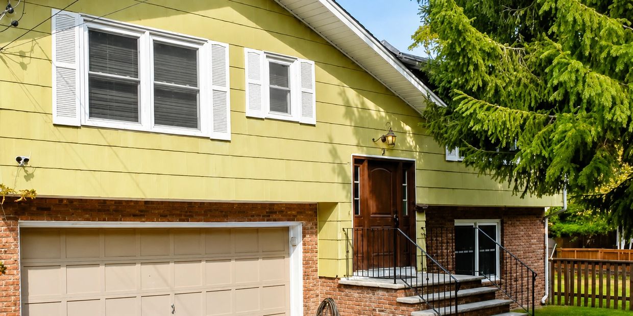 Yellow house with brick foundation and garage.