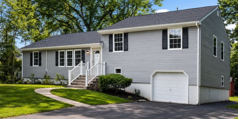 A gray suburban house with a white garage door and front porch.