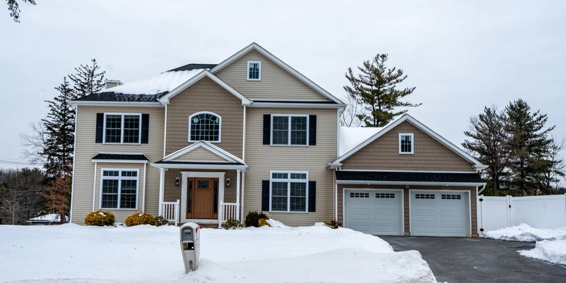 Large house with snow-covered yard and driveway.