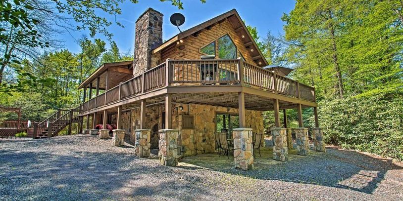 A rustic stone and wood cabin surrounded by lush green trees.