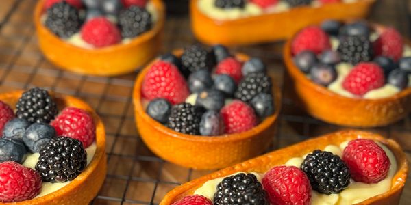 Mini fruit tarts topped with fresh raspberries, blackberries, and blueberries.