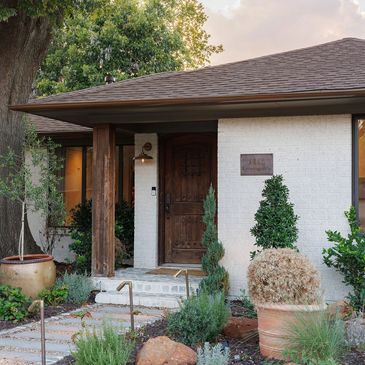 Front entrance of a house with wooden door and plants.