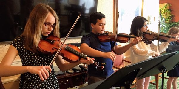 Children playing violins in a music class.