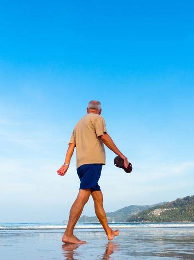 Senior man walking  on a Florida beach, symbolizing calm and healing with virtual EMDR therapy.