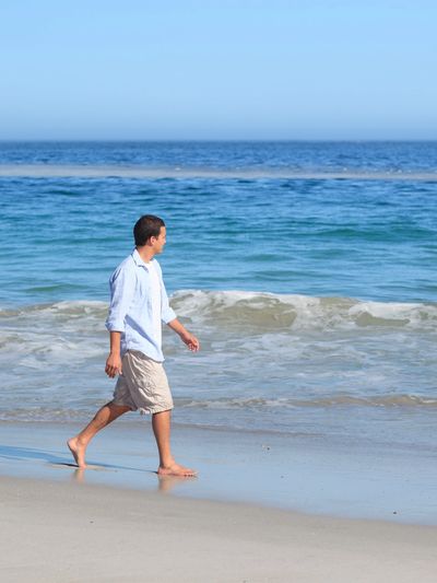 Confident young man walking on a Florida beach after self-esteem counseling