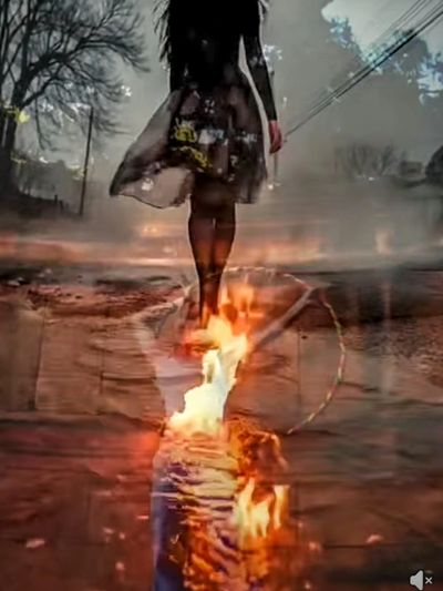A person walking toward fire on a street at dusk