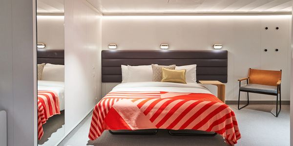 Modern bedroom with a comfortable bed and vibrant red striped blanket.