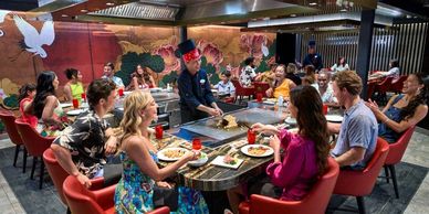 Group enjoying teppanyaki dinner with chef cooking at the table.