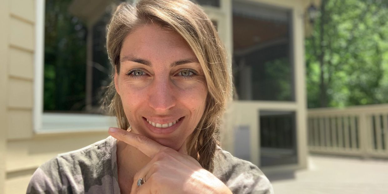 Woman smiling outdoors in natural light.