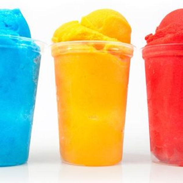 Three colorful shaved ice cups in blue, yellow, and red flavors.