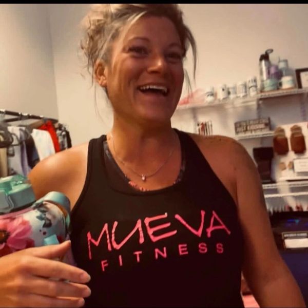 Smiling woman in a Mueva Fitness tank top.