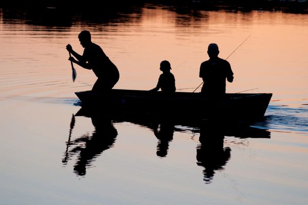 A dad and his boys fishing at sunset