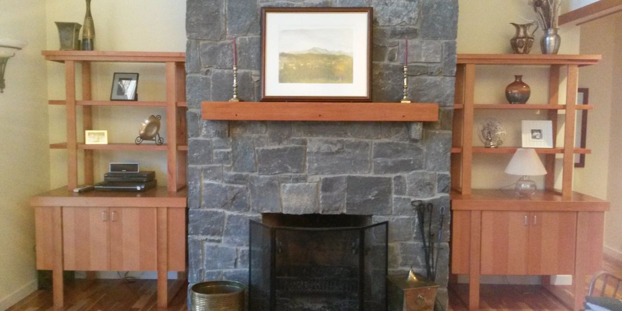 Stone fireplace with wooden shelves on either side.