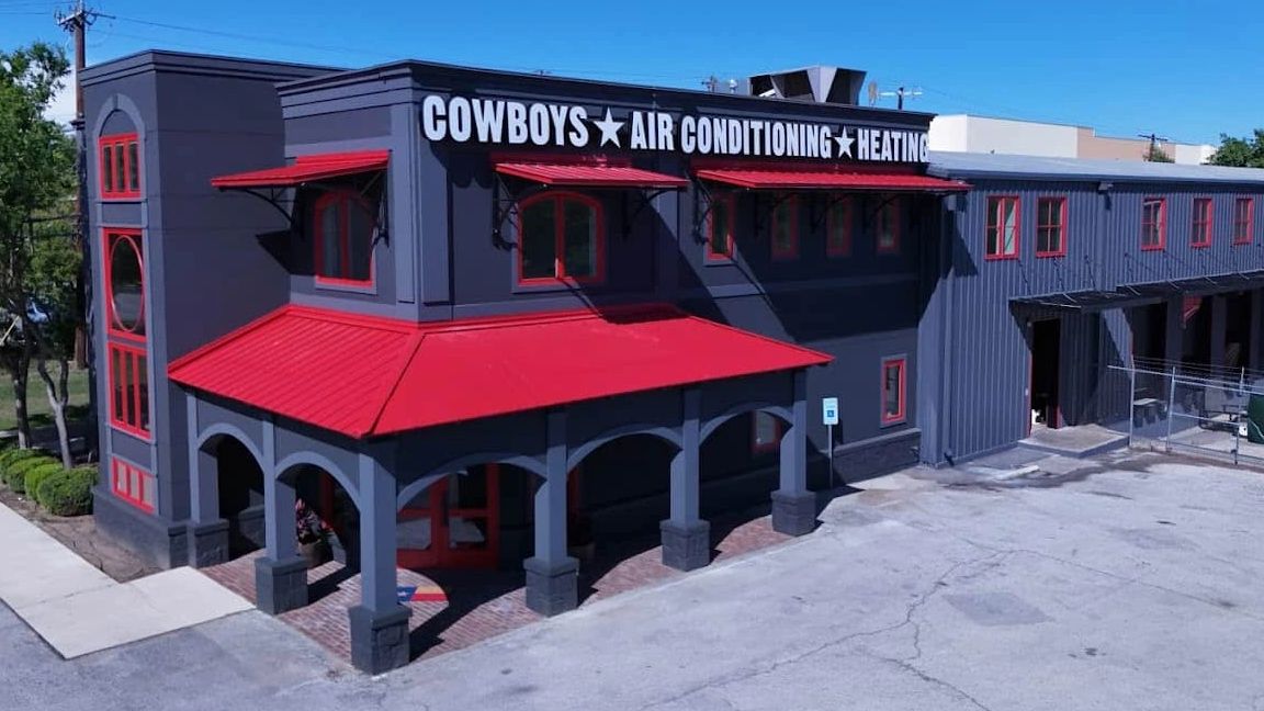 A dark gray and red building with Cowboys Air Conditioning Heating signage.