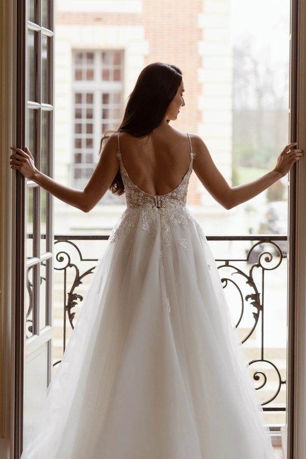 Bride in an elegant backless wedding gown by a balcony.