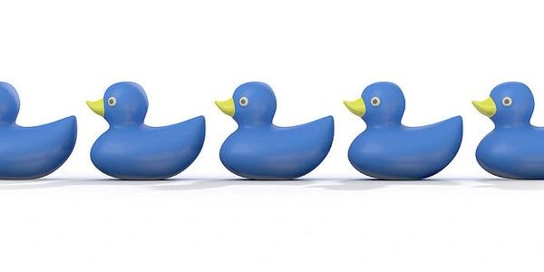 Row of five blue rubber ducks with yellow beaks on a white background.