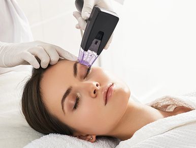 Woman receiving a facial treatment with a high-tech device.