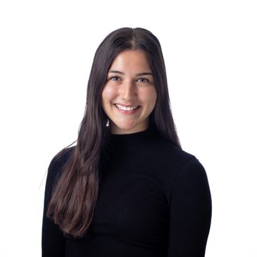 Young woman smiling warmly, wearing a black top against a white background.